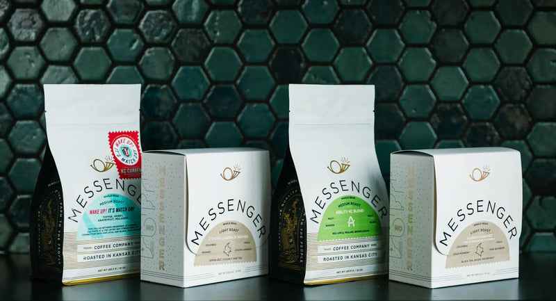Four packaged coffee products from Messenger Coffee Company displayed against a dark hexagonal tile background